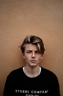 man in black crew-neck shirt near brown wall