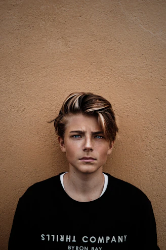 man in black crew-neck shirt near brown wall