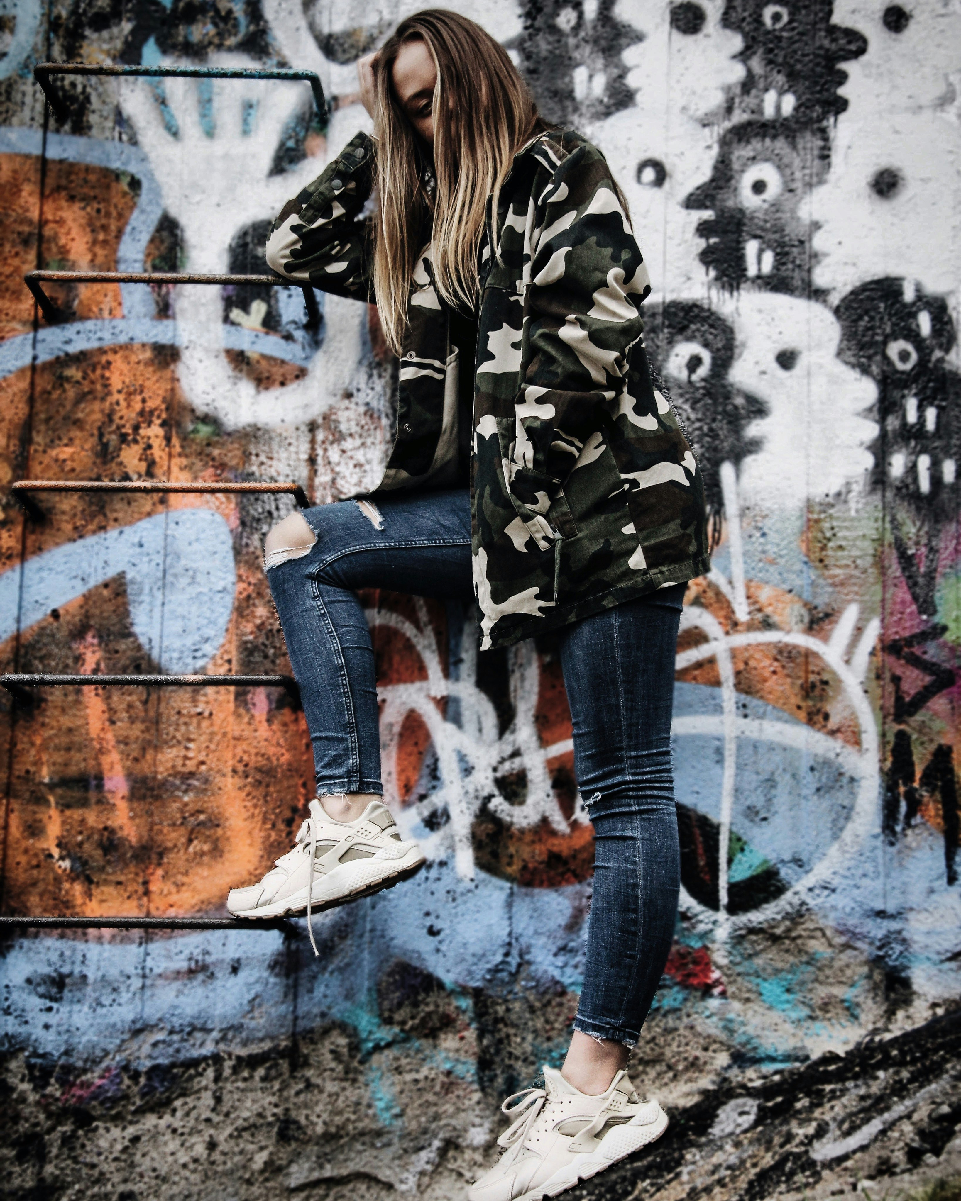 women's gray and black camouflage jacket standing beside wall