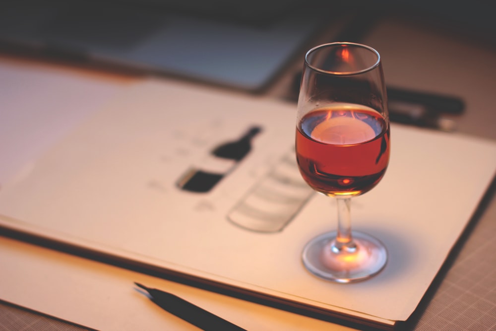 copo de vinho transparente com licor vermelho