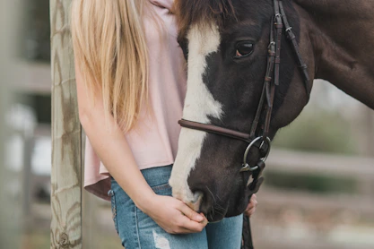 woman standing beside black and white horse at daytime