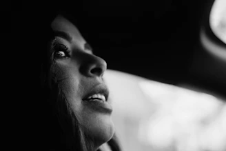 Black and white close-up portrait of a woman with soft natural lighting highlighting her features.