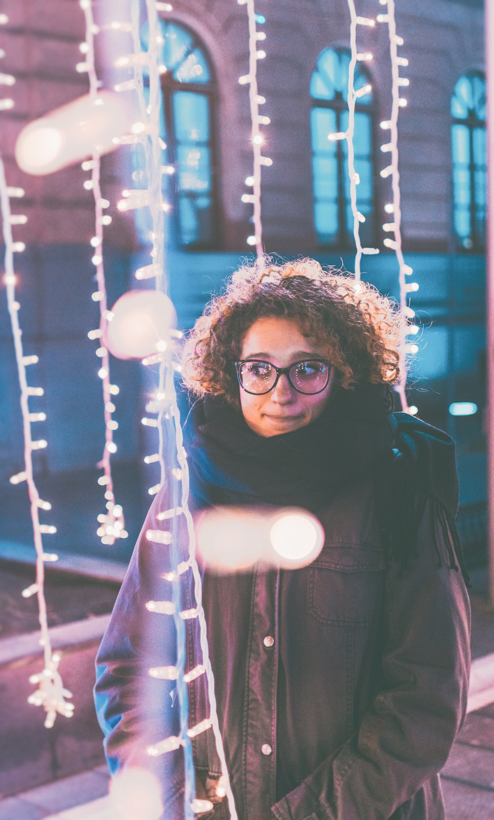 woman standing under lighted string lights