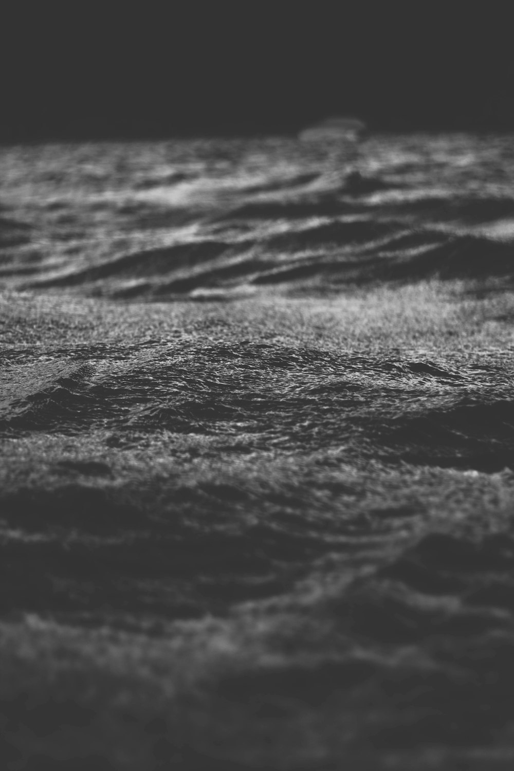 Fotografia em tons de cinza de foco seletivo de areia