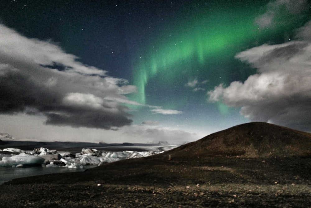 green aurora borealis on brown hill