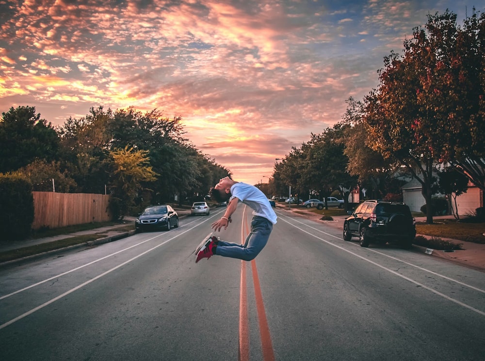 Homem pulando na estrada durante a hora dourada