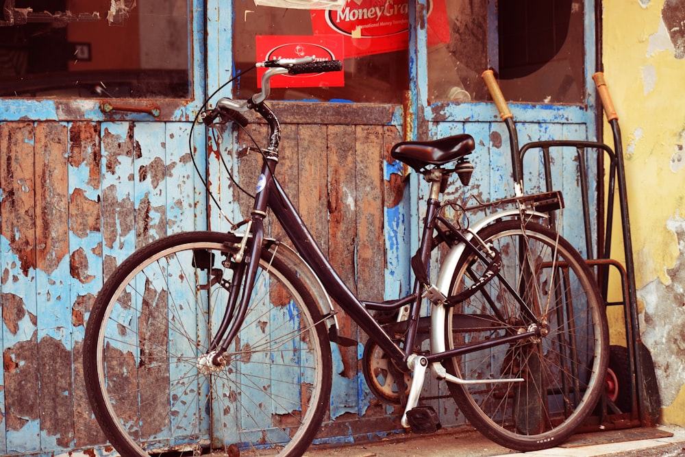 vélo cruiser noir et gris devant la porte en bois bleu