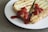 Two slices of toasted cheese sandwich are placed on a white plate. The sandwich is topped with a generous amount of ketchup. The bread appears to be grill marked and crispy, and the filling consists of melted cheese.