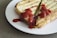 Two slices of toasted cheese sandwich are placed on a white plate. The sandwich is topped with a generous amount of ketchup. The bread appears to be grill marked and crispy, and the filling consists of melted cheese.