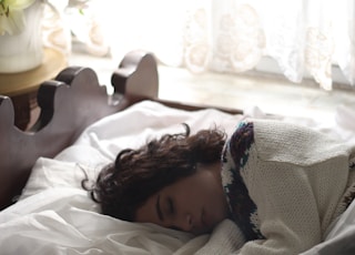 woman sleeping on bed beside book