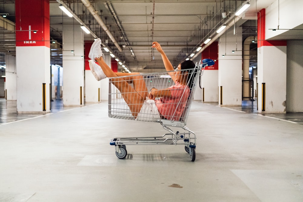 woman sitting in shopping cart at parking lot