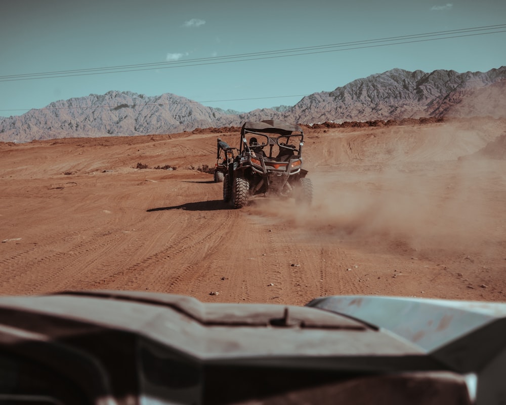 black and red ATV travelling on desert