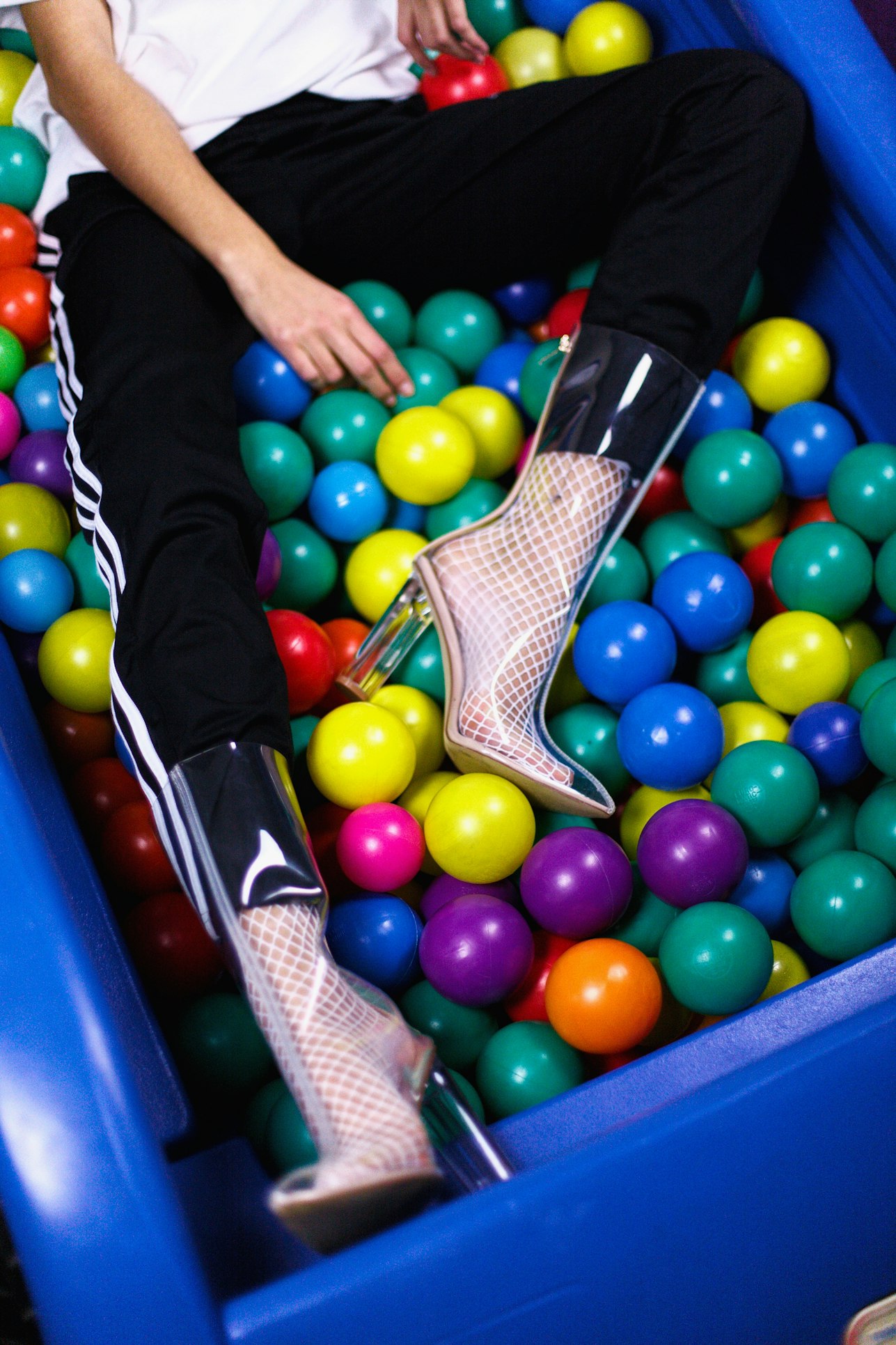 Mujer con botines transparentes en tendencia en una pisicna de bolas