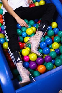 person sitting on assorted-color plastic ball lot
