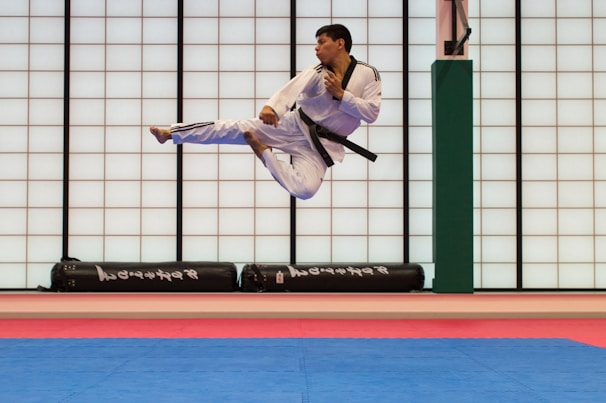A martial artist executing a high kick in a dimly lit ring, spotlight highlighting the motion