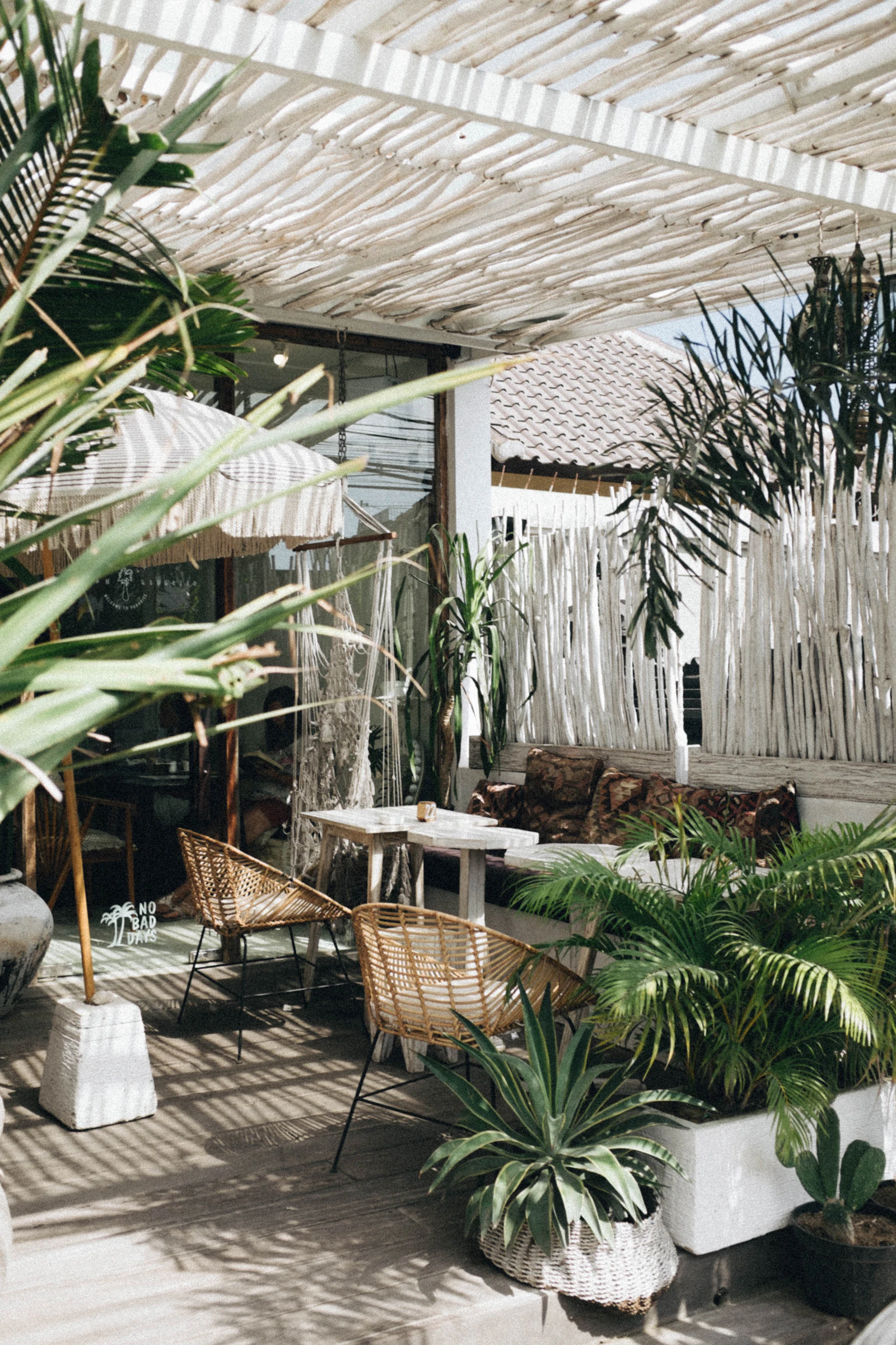 A patio set with wicker chairs surrounded by plants