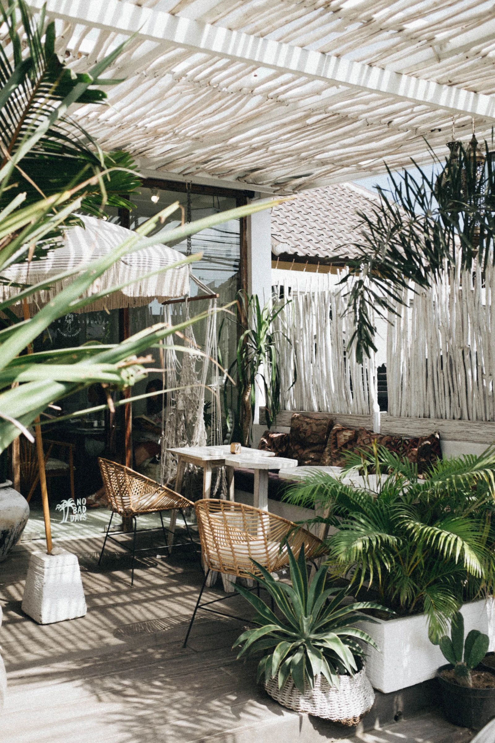 A wicker chair and table on a planted veranda