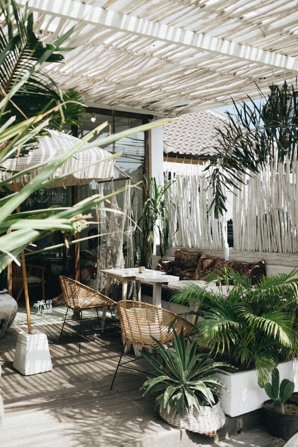 Table blanche avec chaise en osier brun à côté de plantes