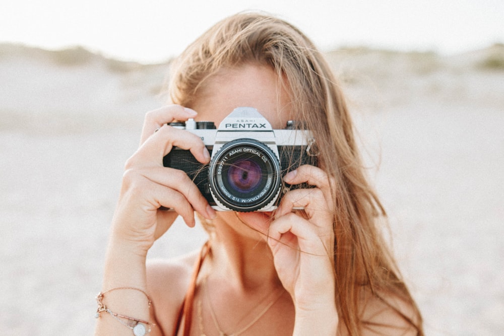 Frau fotografiert mit silberner Pentax-Kamera