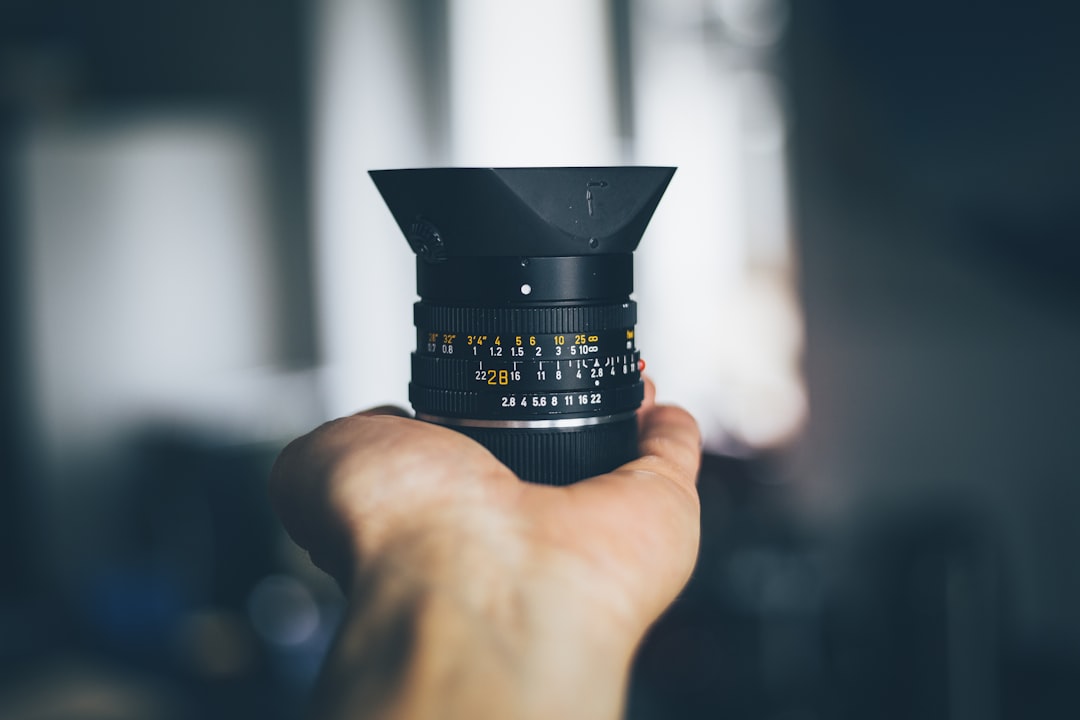 person holding black DSLR camera lens,