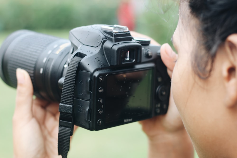woman taking photos using Nikon DSLR camera during daytime