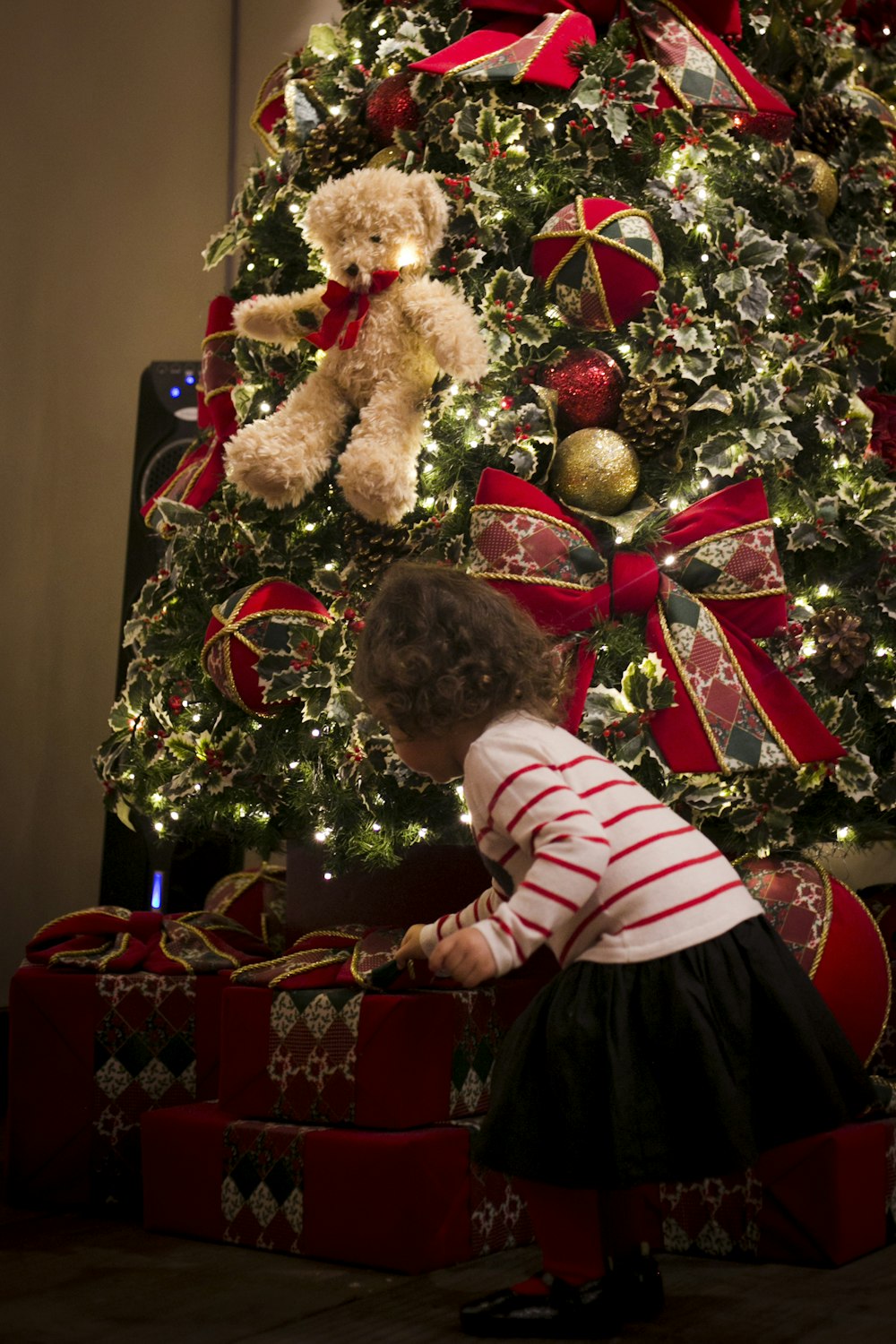 muchacha recogiendo el regalo frente al árbol preiluminado