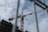 A construction crane towering over a building site with scaffolding, set against a partly cloudy sky. The crane is yellow and bears the name 'SDK'.