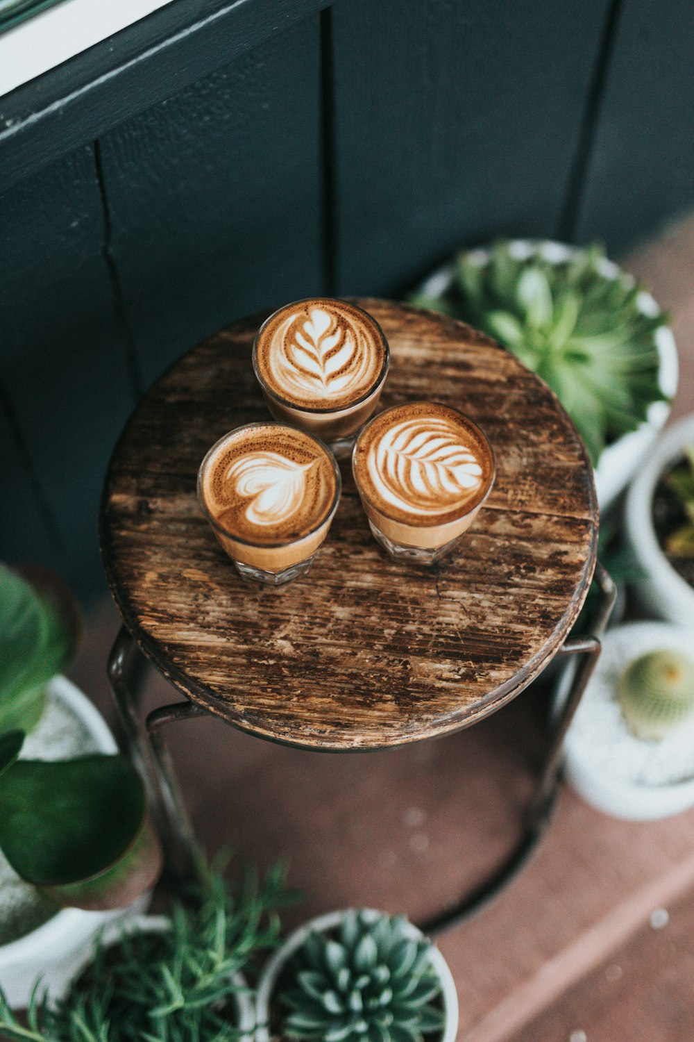 three cups of coffees on round brown wooden stools