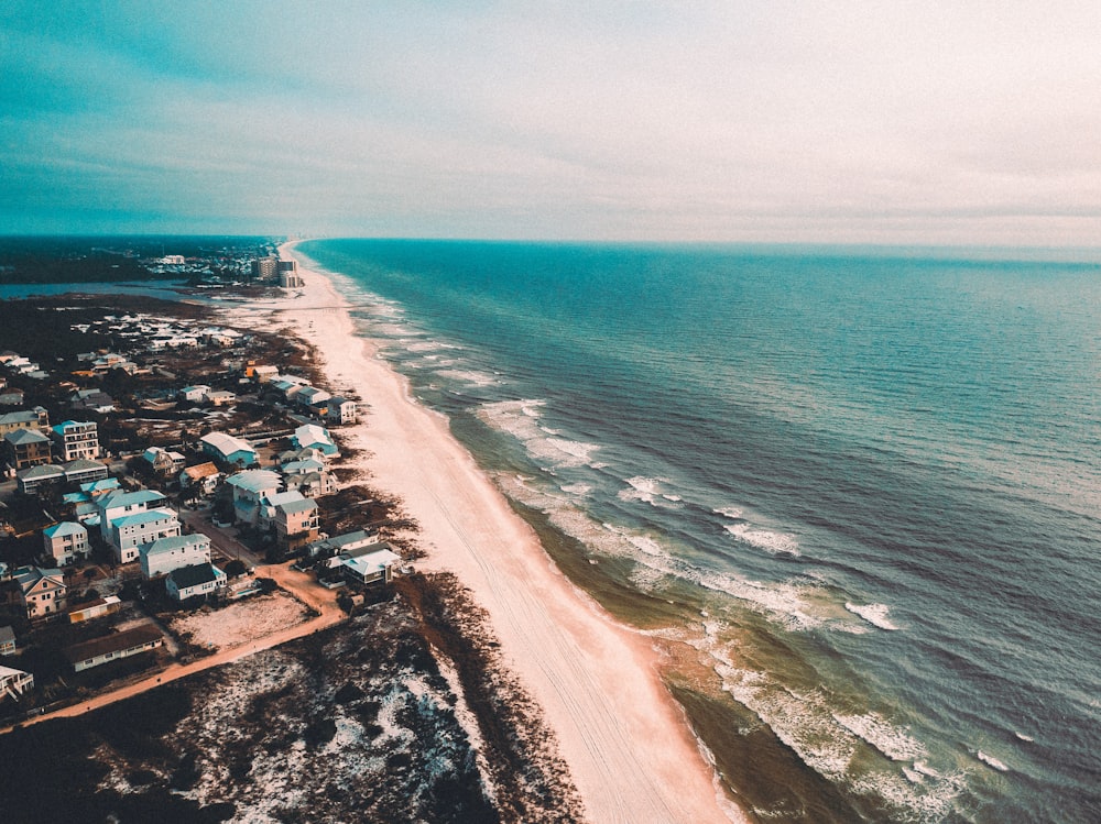 foto aérea do caminho da orla da praia entre casas e corpo d'água