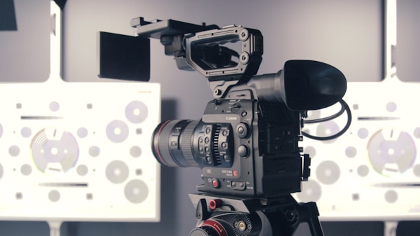 A professional video camera is mounted on a tripod, positioned in front of a technical test chart with various circles and patterns, typically used for calibrating cameras.