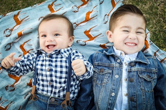two boys laying on blue textile throw in their garden picture taken from above