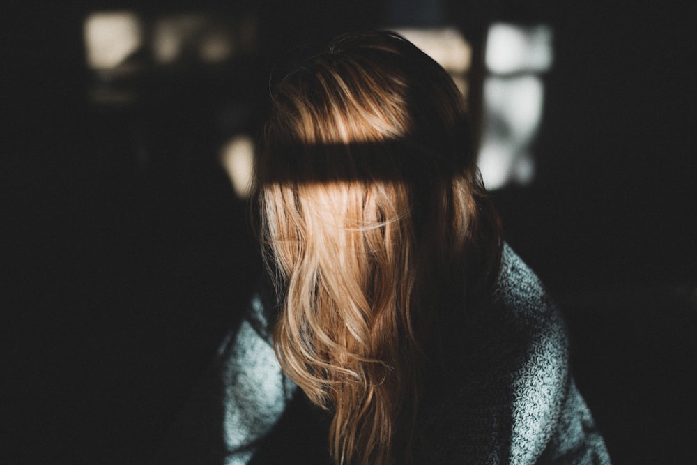 uma mulher com cabelo comprido em pé em um quarto escuro