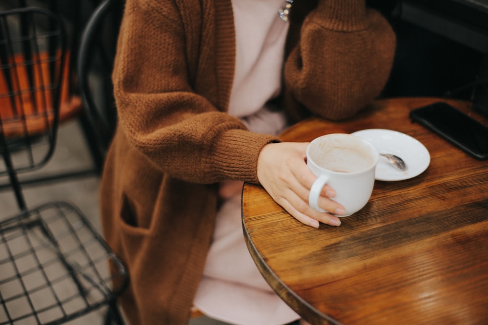 woman sitting on chair while holding white mug