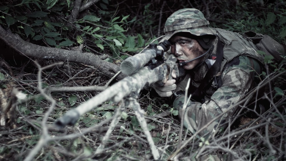 Scharfschütze mit Scharfschützengewehr in der Nähe von Pflanzen