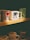 A collection of coffee mugs displayed on a shelf. The prominent mugs include one with 'I ❤ NY' in bold letters, another with a skull and crossbones design labeled 'Death Before Decaf', and a green mug featuring a mermaid pattern. The lighting casts a warm, cozy ambiance over the scene.