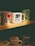 A collection of coffee mugs displayed on a shelf. The prominent mugs include one with 'I ❤ NY' in bold letters, another with a skull and crossbones design labeled 'Death Before Decaf', and a green mug featuring a mermaid pattern. The lighting casts a warm, cozy ambiance over the scene.