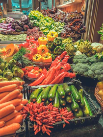 A colorful display of fresh bell peppers and zucchinis arranged neatly on a market stall.