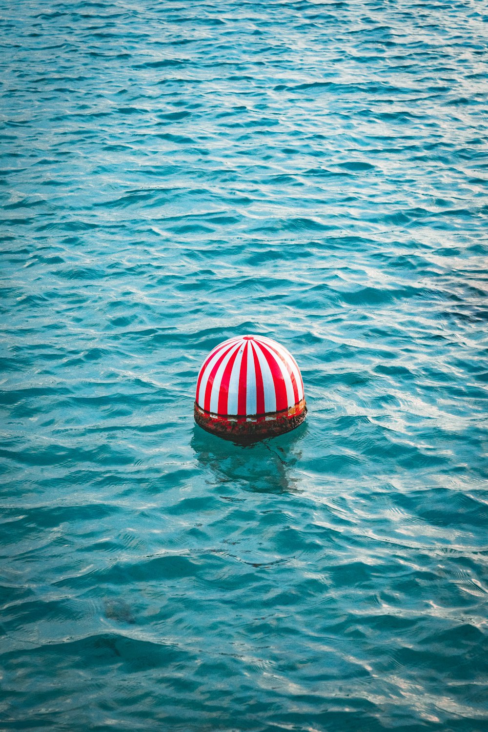 red and white buoy on body of water during daytime
