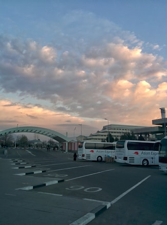 A fleet of rental cars, buses, and tempo travelers ready for departure under a bright sky.