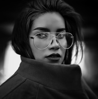 grayscale photo of woman wearing coat and eyeglasses