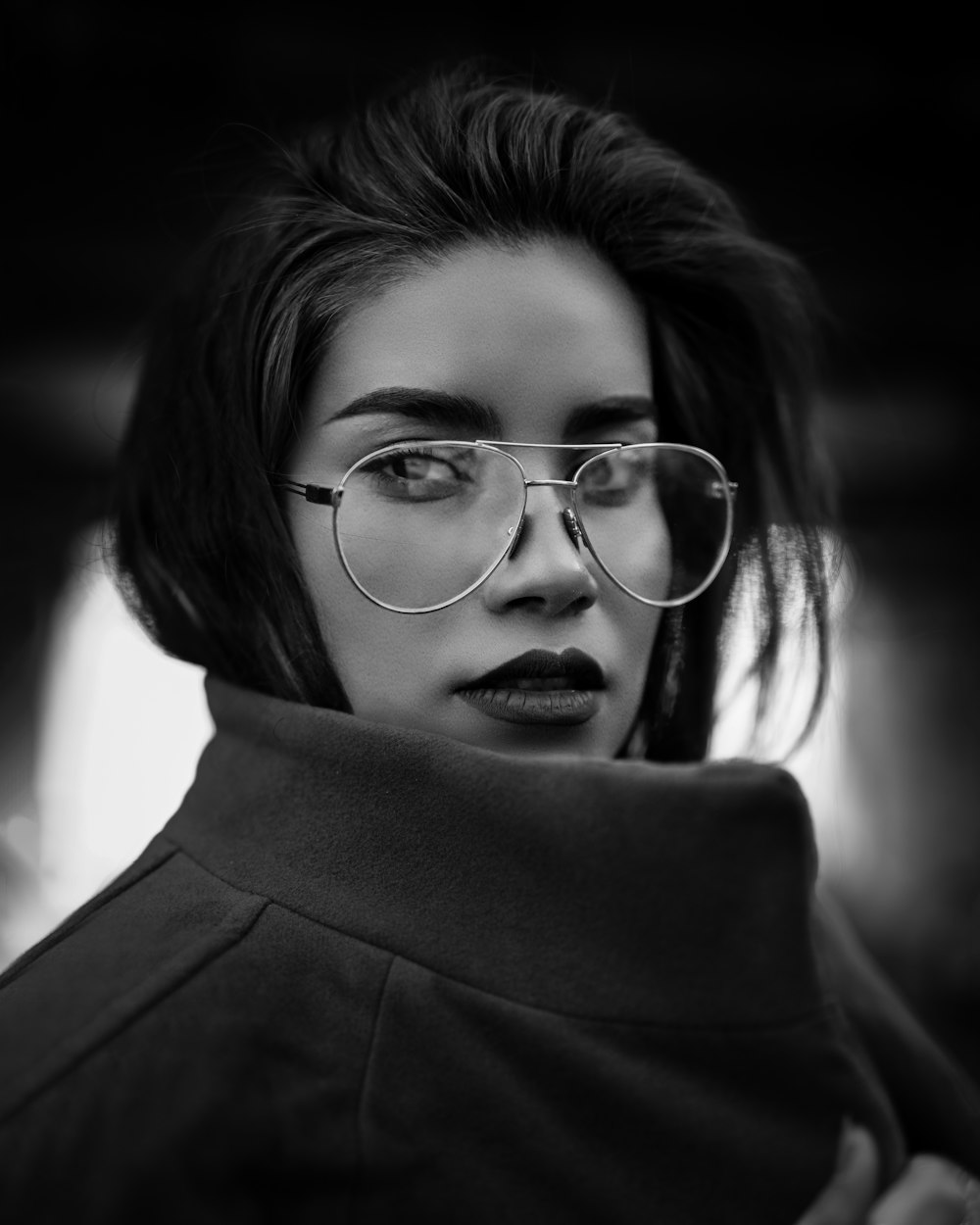 grayscale photo of woman wearing coat and eyeglasses