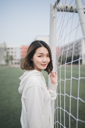 man in white pullover hoodie standing beside white goal net
