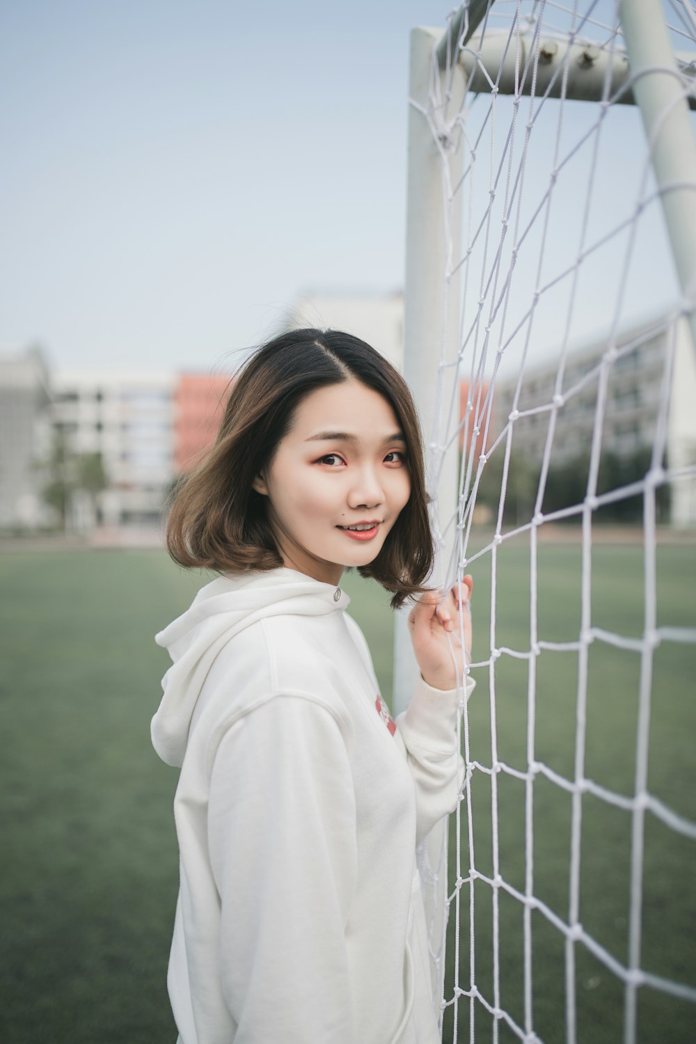 man in white pullover hoodie standing beside white goal net