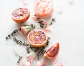 sliced blood orange fruits with white-and-pink petaled flowers beside