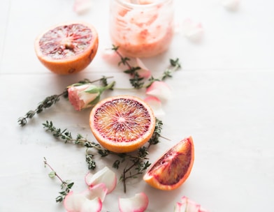 sliced blood orange fruits with white-and-pink petaled flowers beside