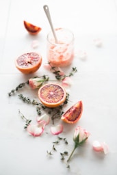 sliced blood orange fruits with white-and-pink petaled flowers beside