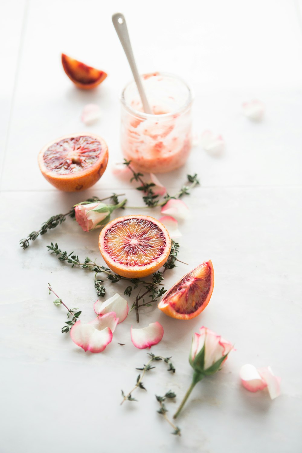 frutas alaranjadas cortadas com flores de pétalas brancas e rosas ao lado