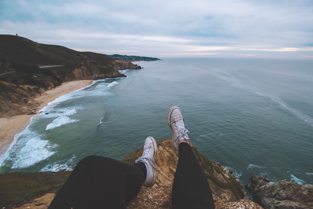 person sitting on cliff rock