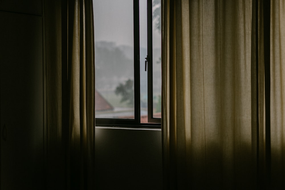 black metal framed glass window open with brown curtain