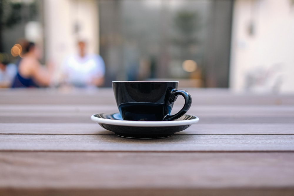 black ceramic teacup on brown surface